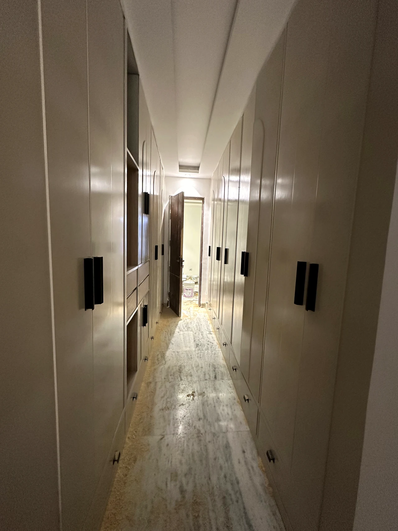 Hallway view through the home, showing the marble-look floor and fitted doors