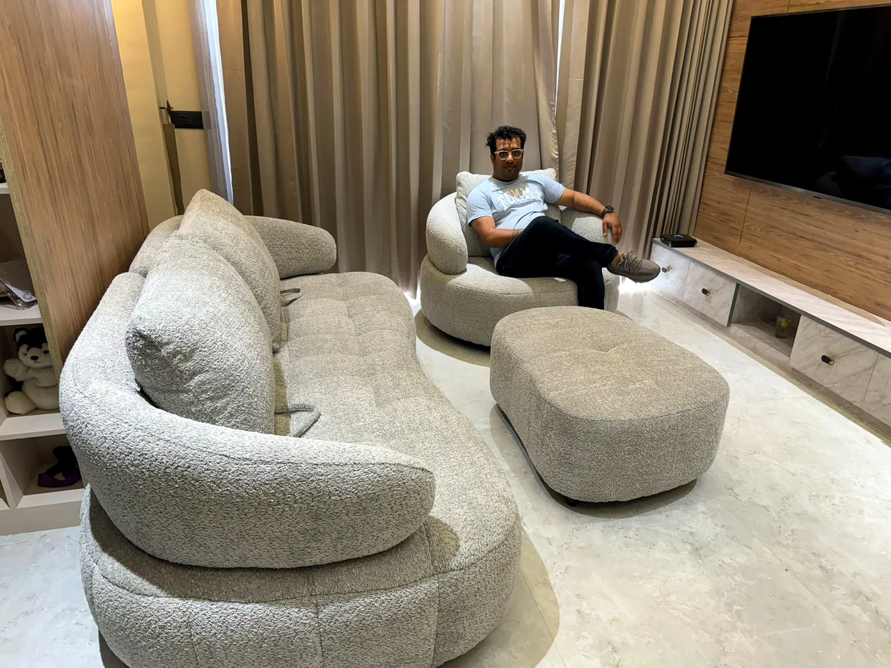 Curved sectional seating with a round ottoman and timber feature wall
