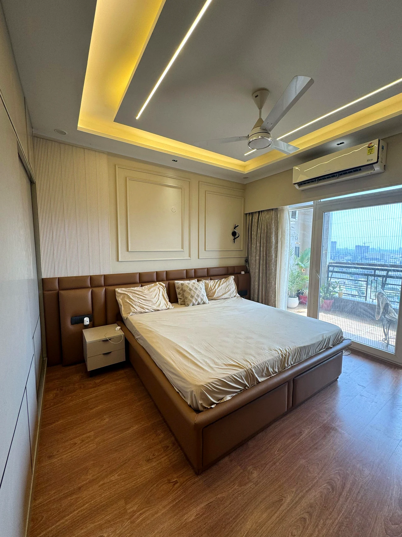 Bedroom with warm wood floor, paneled headboard and neutral bedding